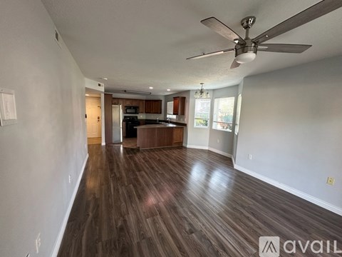 A spacious room with a ceiling fan and wooden flooring.