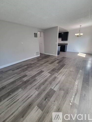 A room with wooden flooring and a television in the corner.