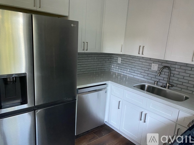 A kitchen with a stainless steel refrigerator and white cabinets.