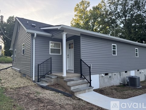A small house with a porch and a white door is available for rent.