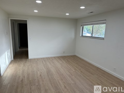 A room with wooden flooring and a window with a view of trees outside.
