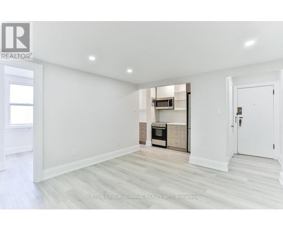 A white room with a kitchenette in the corner.