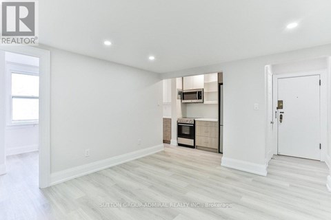 A white room with a kitchenette in the corner.