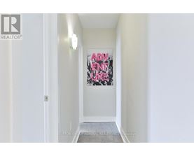 A hallway with a painting on the wall and a door on the left.