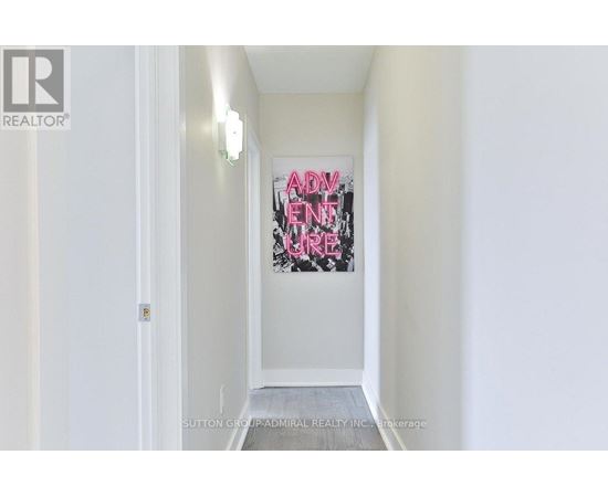 A hallway with a painting on the wall and a door on the left.
