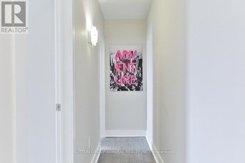 A hallway with a painting on the wall and a door on the left.