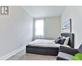 A bedroom with a bed, chair, and painting on the wall.