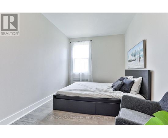 A bedroom with a bed, chair, and painting on the wall.