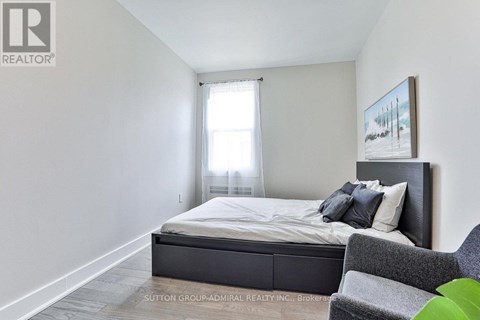 A bedroom with a bed, chair, and painting on the wall.