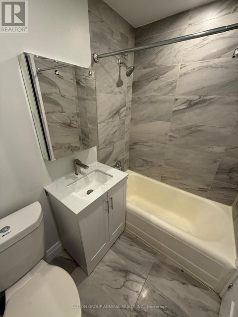 A bathroom with a marble tile wall and a white sink.