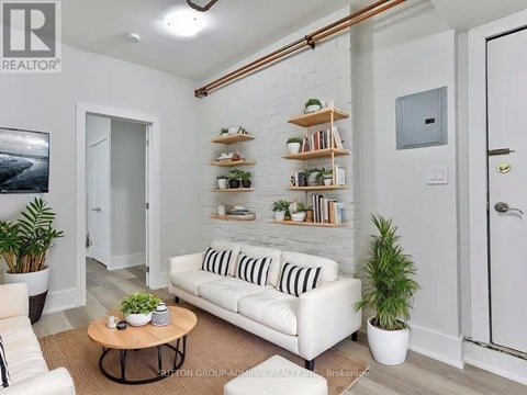A living room with a white couch, a coffee table, and a plant.