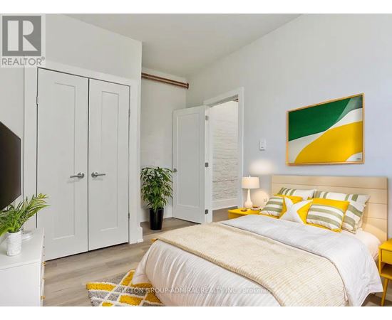 A bedroom with a bed, a lamp, a potted plant, and a painting on the wall.