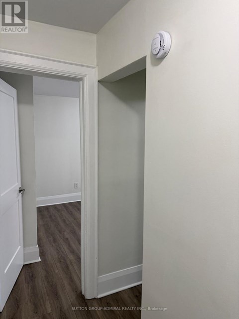 A hallway with a door on the left and a wall on the right.