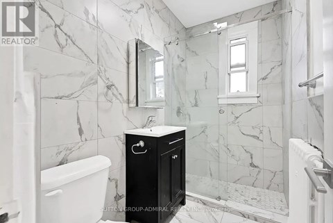 A bathroom with marble walls and a black cabinet.