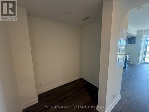 A room with wooden flooring and white walls, with a door visible in the background.