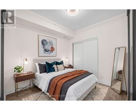 A bedroom with a bed, a mirror, and a painting on the wall.