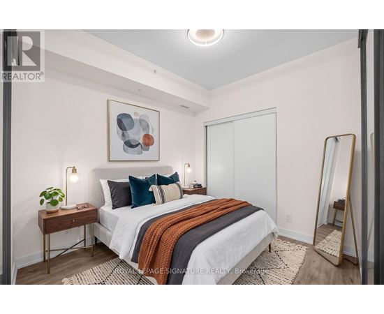 A bedroom with a bed, a mirror, and a painting on the wall.