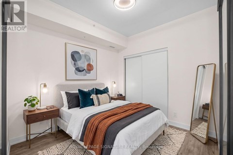 A bedroom with a bed, a mirror, and a painting on the wall.