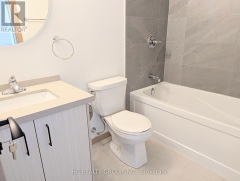 A white toilet sits next to a white sink in a bathroom.