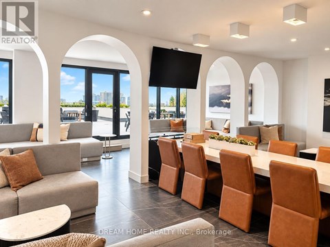 A modern living room with a large couch, a dining table with chairs, and a flat-screen TV mounted on the wall.