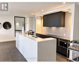 A modern kitchen with a white island and black cabinets.