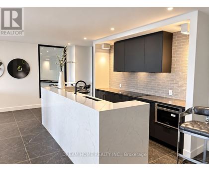 A modern kitchen with a white island and black cabinets.