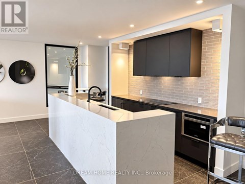 A modern kitchen with a white island and black cabinets.