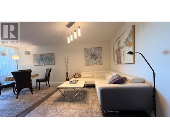 A living room with a white couch, a coffee table, and a painting on the wall.