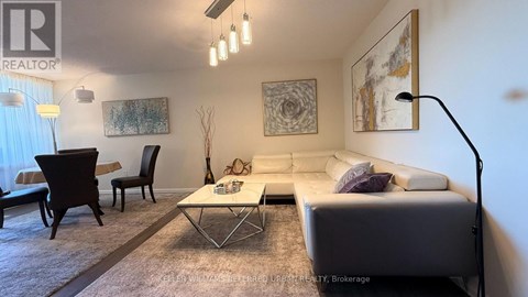 A living room with a white couch, a coffee table, and a painting on the wall.