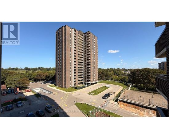 A tall residential building with a parking lot in front.