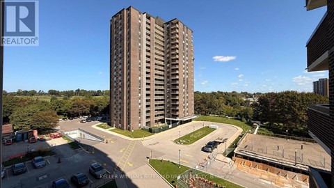 A tall residential building with a parking lot in front.