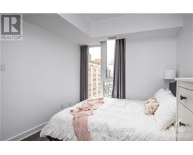 A bedroom with a large bed and a window overlooking a cityscape.
