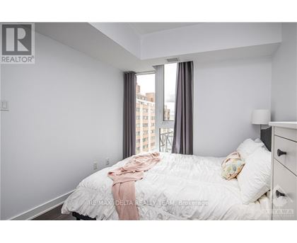 A bedroom with a large bed and a window overlooking a cityscape.