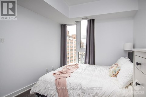 A bedroom with a large bed and a window overlooking a cityscape.
