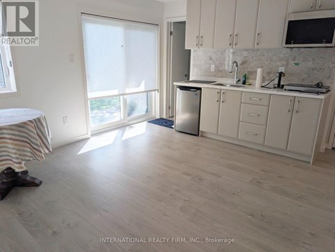 A kitchen with white cabinets and a wooden floor.