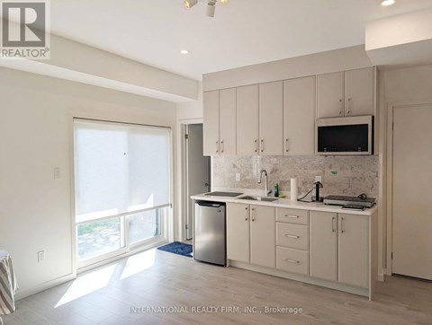A kitchen with white cabinets and a flat screen TV mounted above the sink.