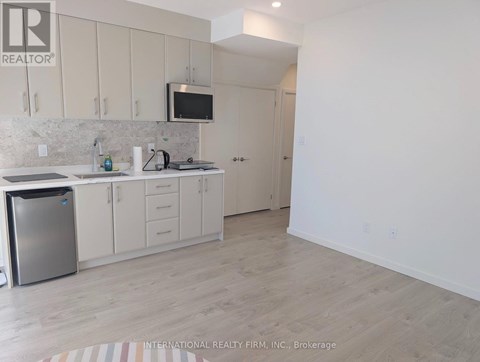 A kitchen with white cabinets and a refrigerator.