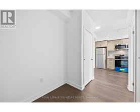 A white room with a doorway leading to a kitchen.