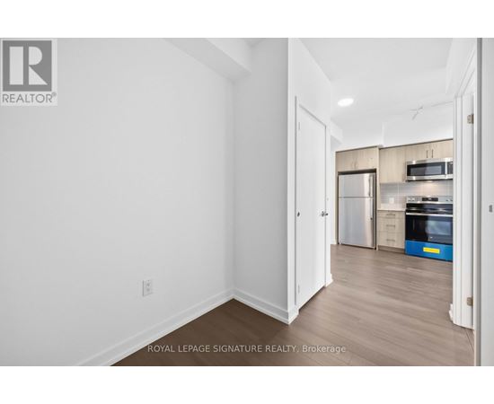 A white room with a doorway leading to a kitchen.