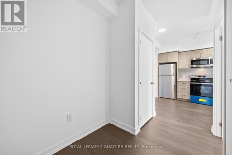 A white room with a doorway leading to a kitchen.