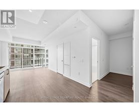 A spacious room with wooden flooring and white walls, with a glass door leading to another room.