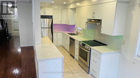 A kitchen with white cabinets and a purple backsplash.