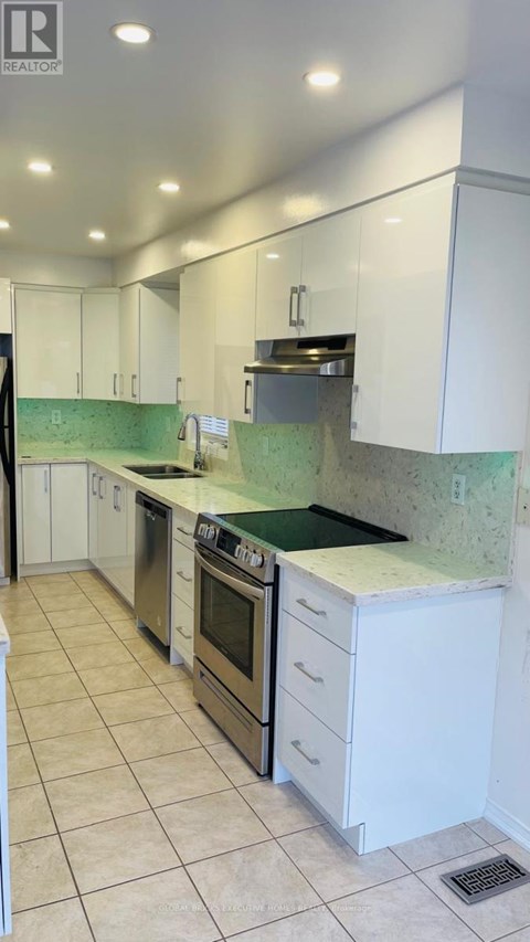 A kitchen with white cabinets and green backsplash.