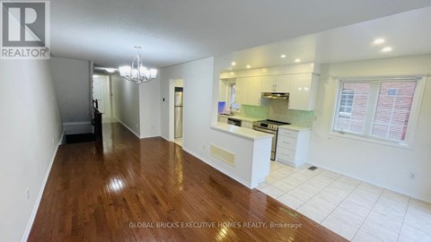 A spacious kitchen with white cabinets and a wooden floor.