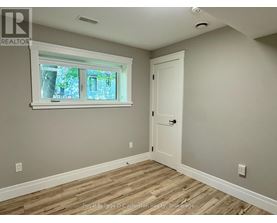 A room with a white door and a window with a view of trees.