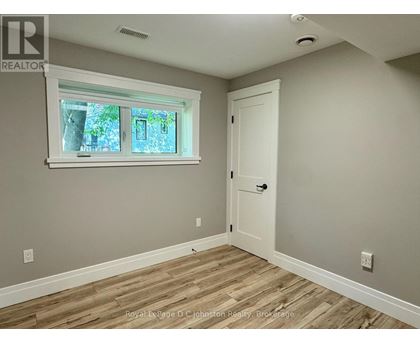 A room with a white door and a window with a view of trees.