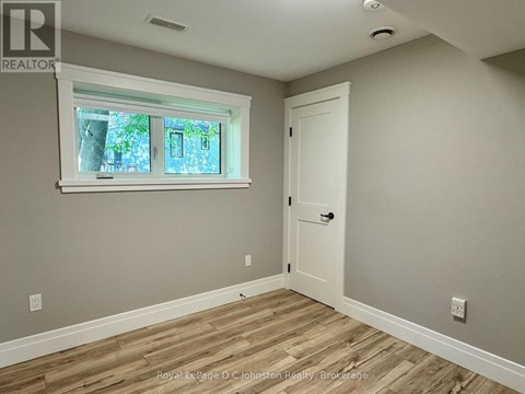 A room with a white door and a window with a view of trees.