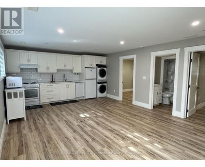 A kitchen with white appliances and wooden floors.
