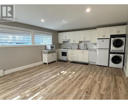 A kitchen with white appliances and wooden floors.