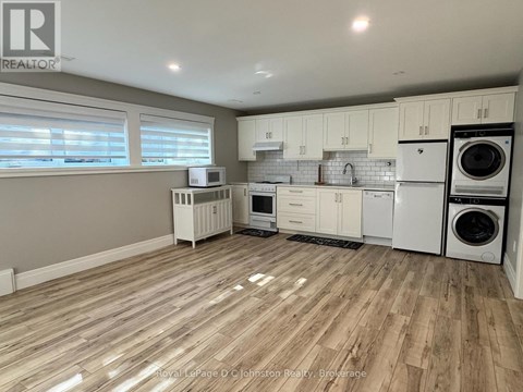 A kitchen with white appliances and wooden floors.